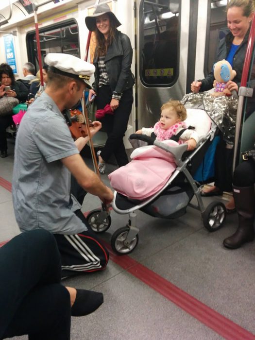 hombre toca el violín para calmar a una niña que lloraba en el metro