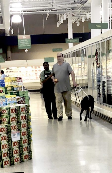 Un empleado ayuda a un invidente a hacer sus compras