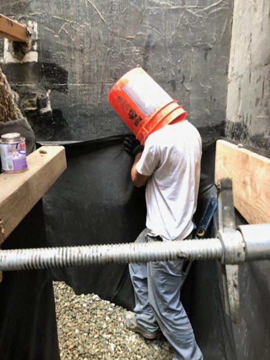 trabajador con balde en la cabeza