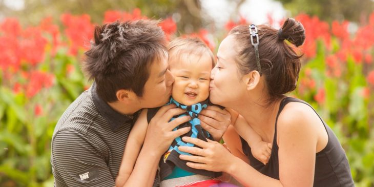 padres besando la mejilla de bebé japonés 