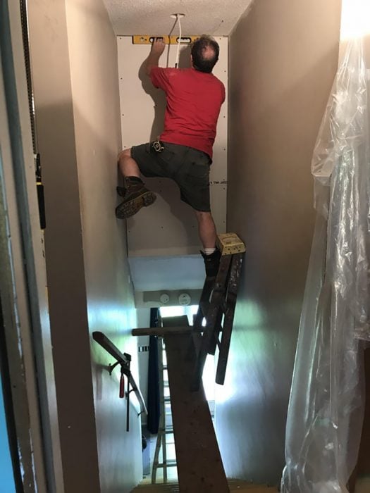 hombre sin protección pintando en el segundo piso de una casa 