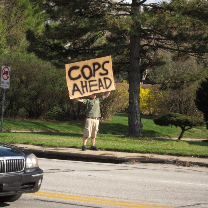 hombre con un cartel que advierte sobre policías 