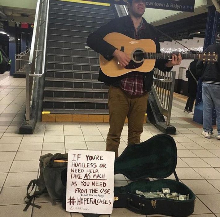 hombre toca la guitarra para recaudar dinero 