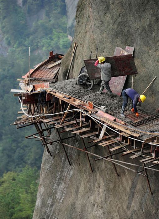 hombres construyendo camino muy pegadito a una colina 