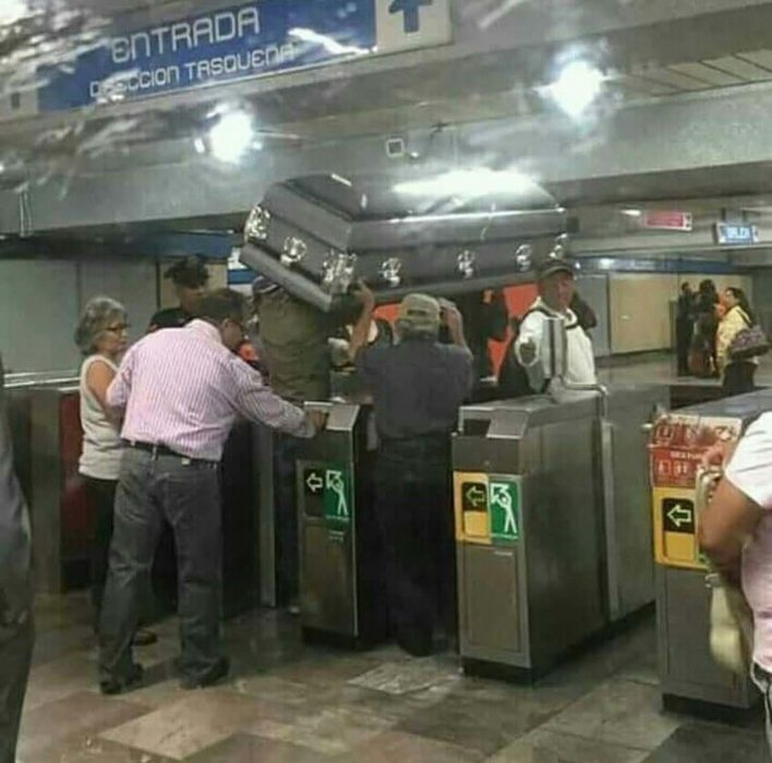 hombres cargando un ataúd antes de subir al metro