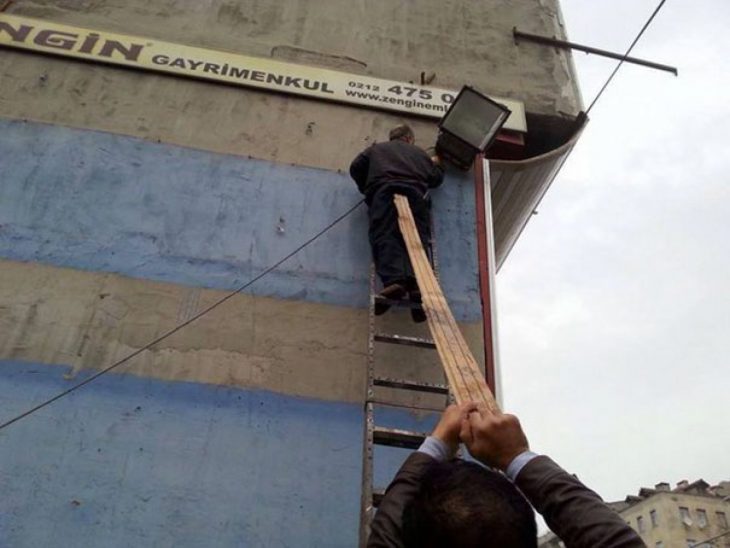 señor en lo alto de una escalera y con un palo en su trasero 