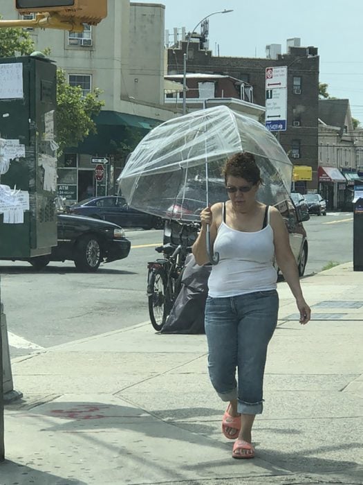 mujer tapándose el sol con paraguas transparente 