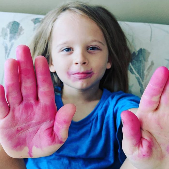 Niño con las manos manchadas de rosa