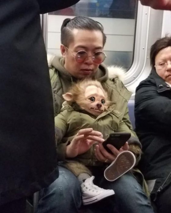 hombre cargando un muñeco monstruo en el metro