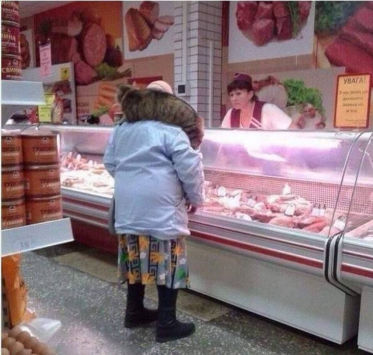 señora comprando carne con su gato en el hombro 
