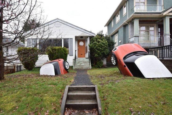 autos enterrados en la tierra frente a una casa 