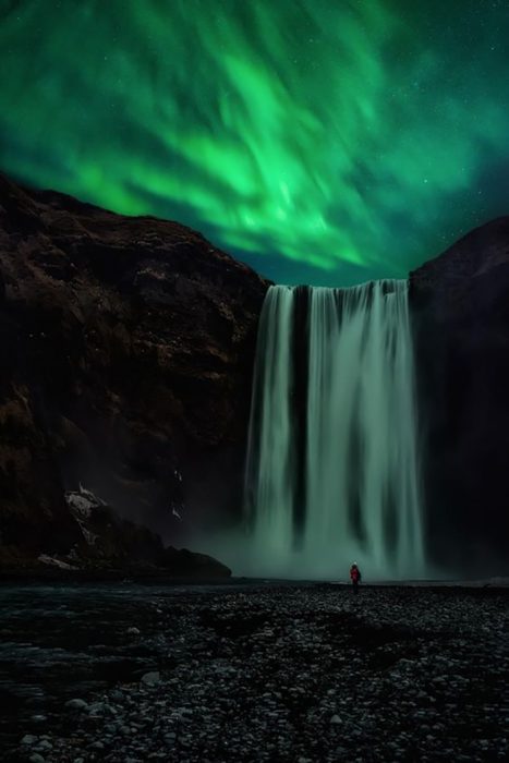 Cascada bajo la aurora boreal en Islandia