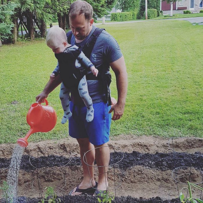 hombre con bebé regando las plantas 