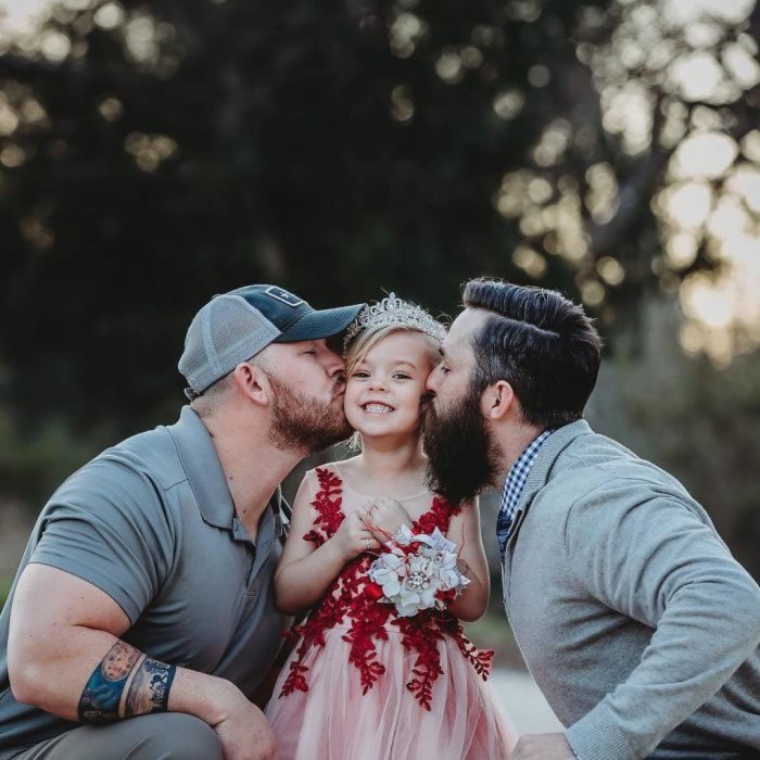 papás besando a niña 